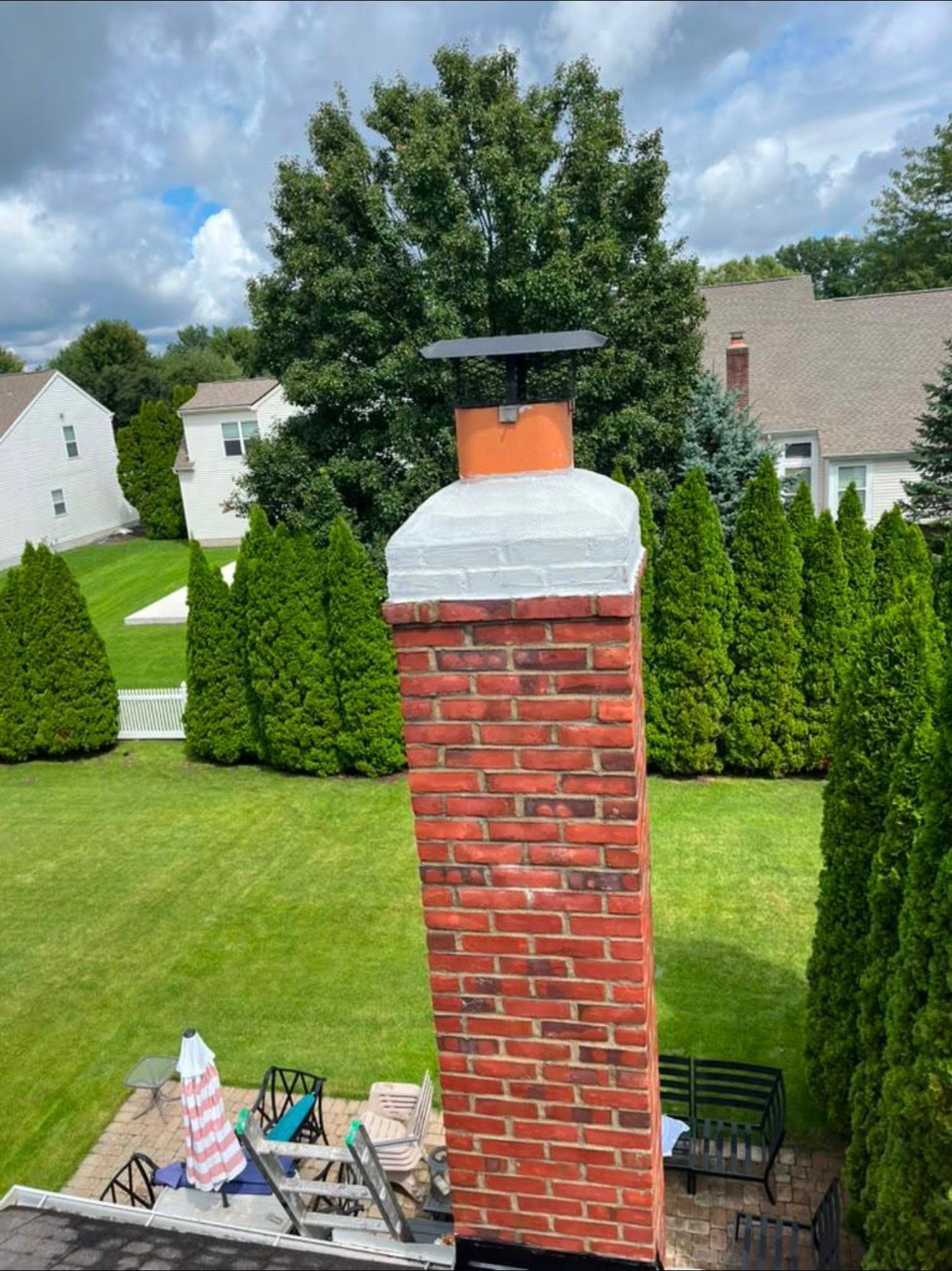 Brick chimney finished with a new black cap and freshly sealed white crown