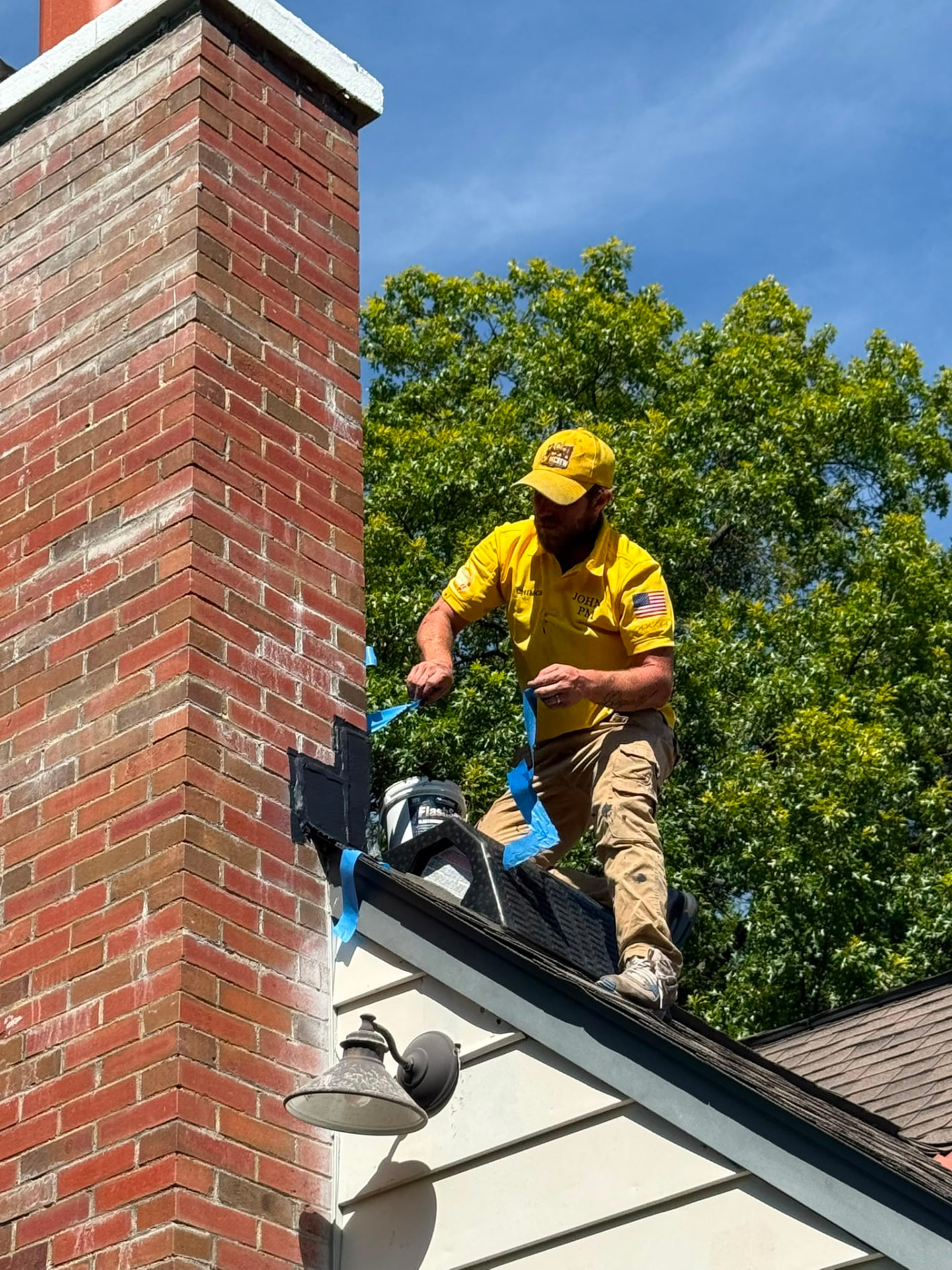 American Chimney & Masonry technician sealing chimney flashing on a rooftop